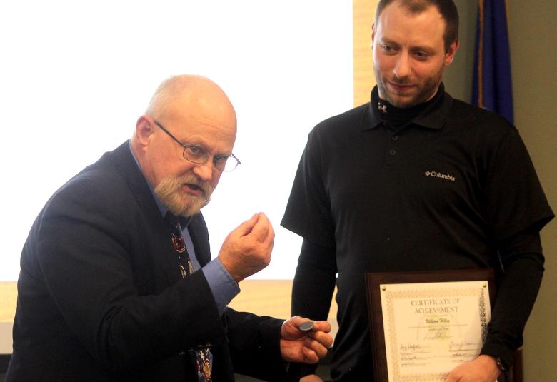 Shawano-Menominee Circuit Court Judge William Kussel Jr., left, presents William Hilley with a medallion, shown in Kussel’s left hand, recognizing that Hilley has completed all the requirements for the Shawano County Drug Treatment Court program during a graduation ceremony Nov. 19 at the Shawano County Human Services Complex.  (Lee Pulaski | NEW Media)